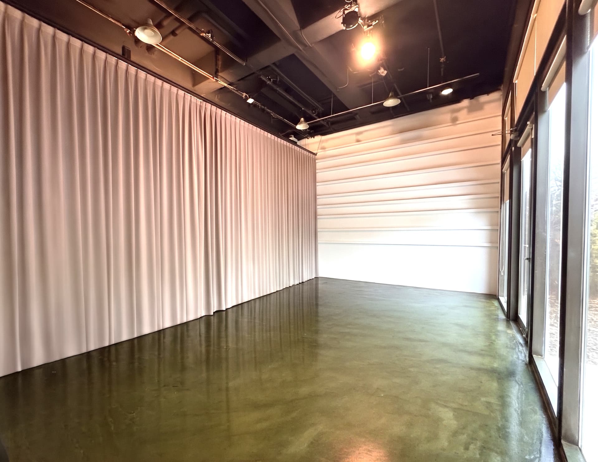 The main room of A39-1: an open floor, a long curtain wall, and street-facing glass doors