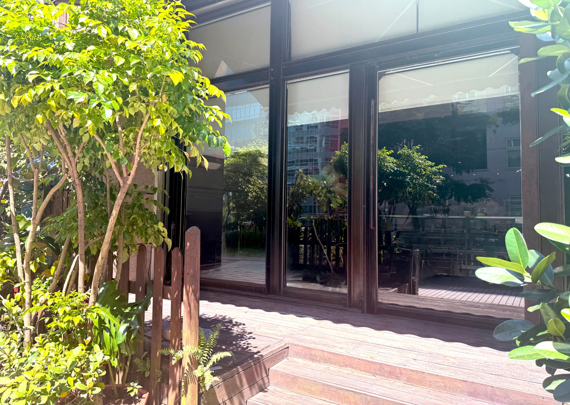 The entrance of A39-1 seen from the wooden deck outside, framed by greenery